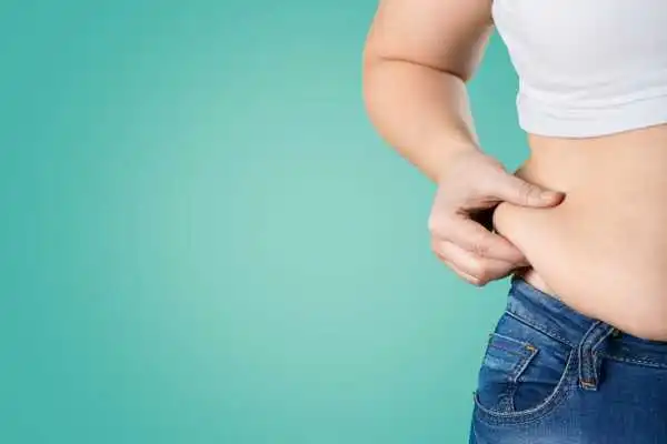 Image of woman pinching her love handles to show weight gain Brentford